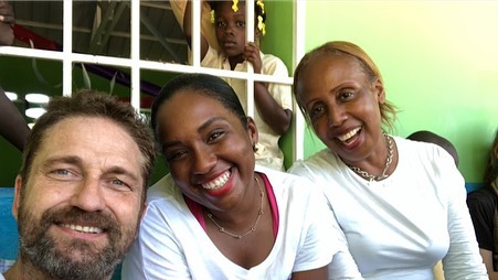 Gerard Butler smiling while serving hot meals to children at a local school during a Mary's Meals humanitarian visit in Africa