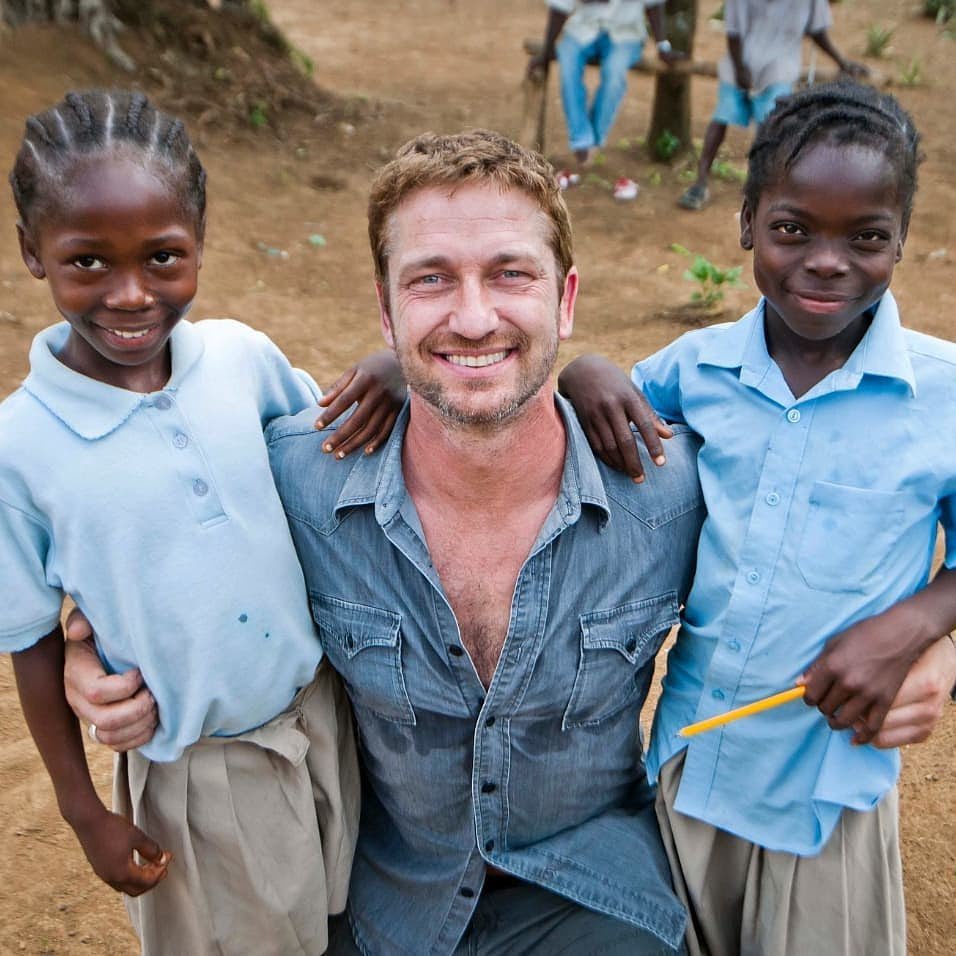 Gerard Butler with local community leaders and schoolchildren outside a newly constructed classroom in Africa