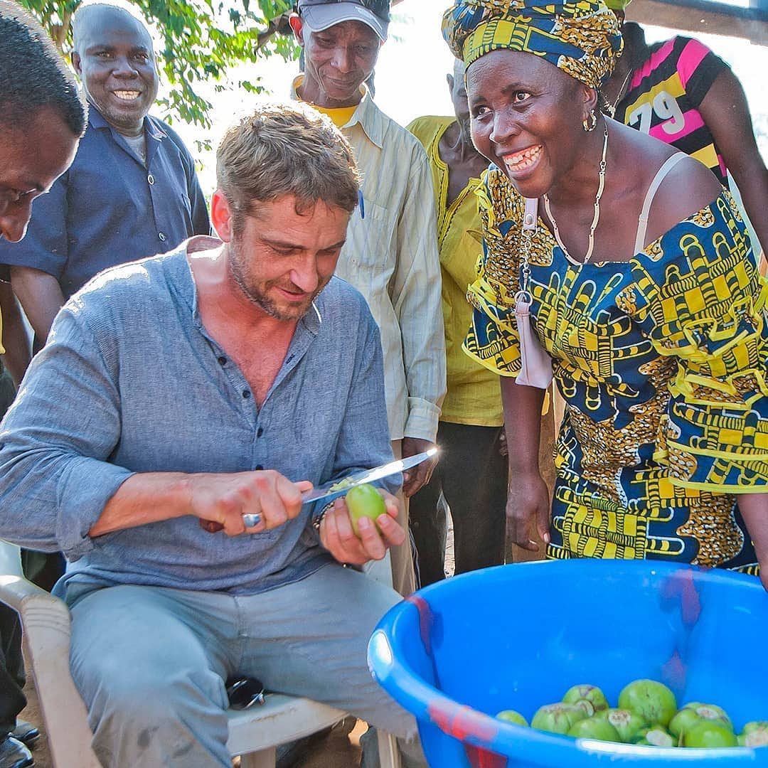 Gerard Butler shaking hands with a teacher at a local community school receiving clean water and nutrition support